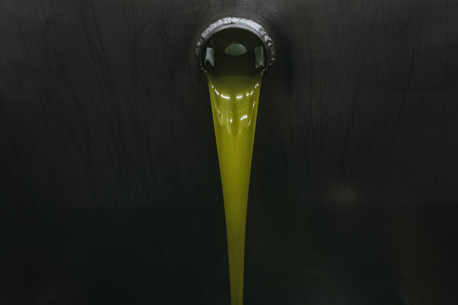 Aceite de oliva virgen fluyendo desde la almazara en un entorno oscuro