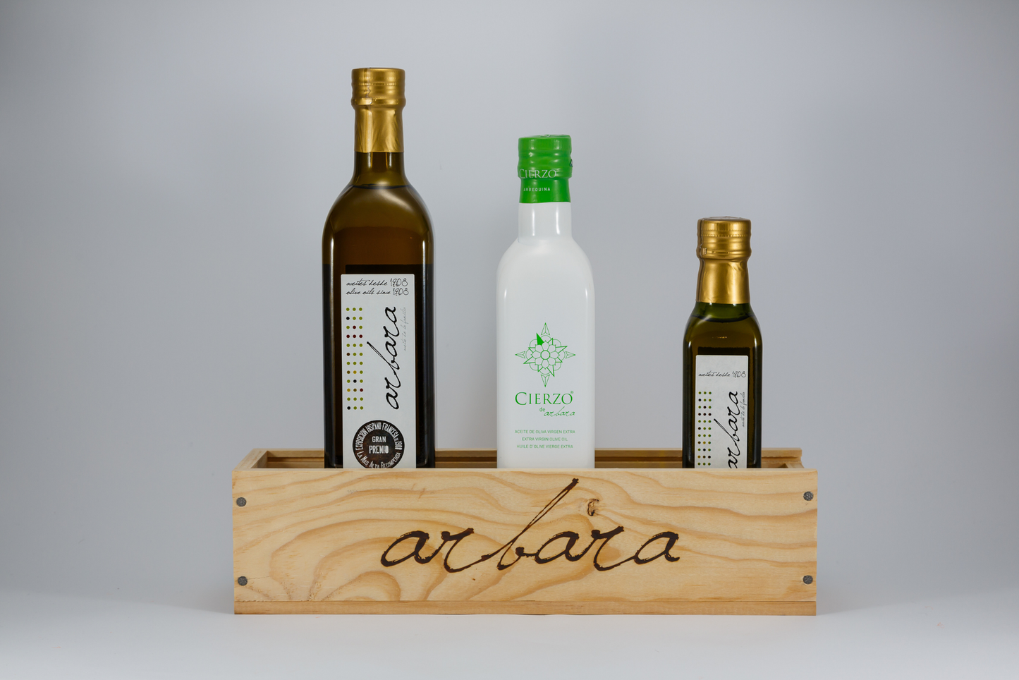 Botellas de aceite de oliva virgen extra Arbara en caja de madera con logotipo, fondo blanco.