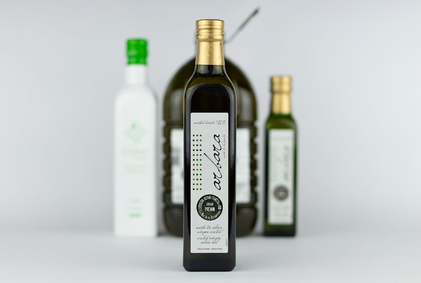 Botella de 500 ml Arbara en primer plano con otras variedades de aceite arbequina al fondo