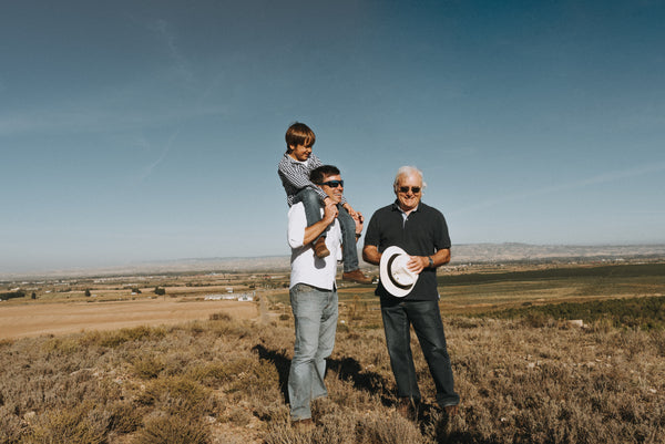 Tres generaciones de la familia Arbara caminando en el campo, simbolizando raíces profundas y valores transmitidos con orgullo.