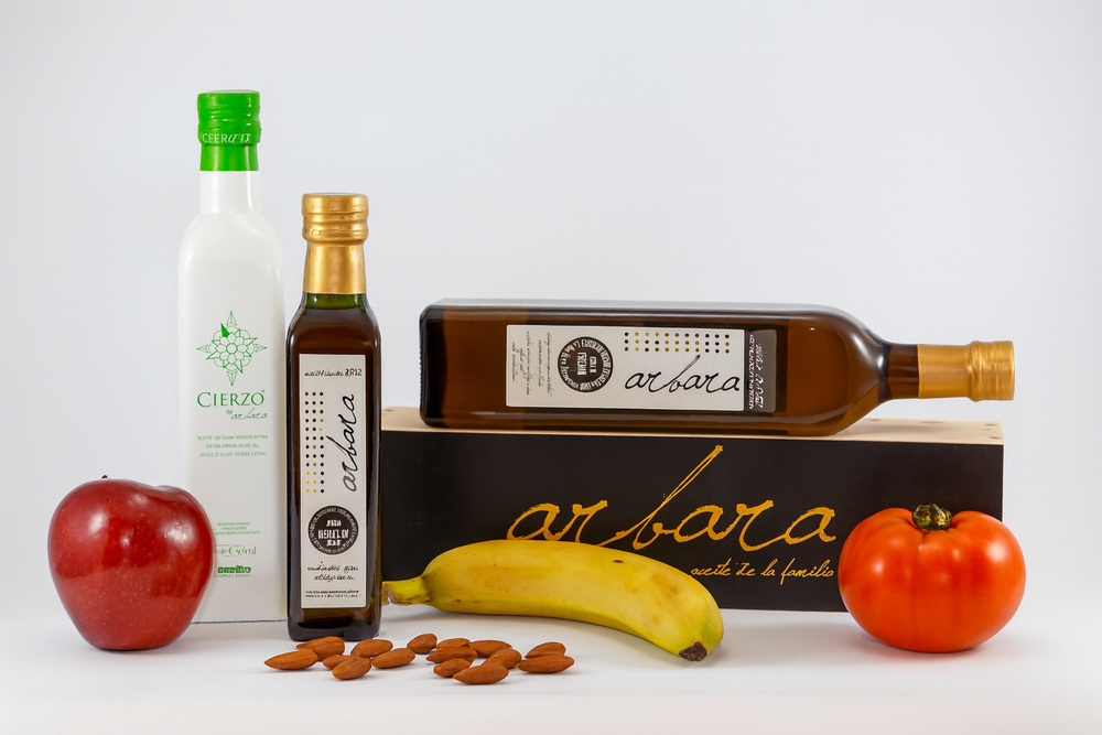 Aceite de oliva virgen extra Arbara y Cierzo con frutas frescas y almendras, ideal para una presentación gourmet y saludable.