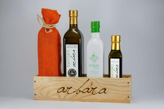Pack de aceites de oliva Arbara y Cierzo en caja de madera, incluyendo una botella grande de Arbara, una botella blanca de Cierzo y una botella pequeña de Arbara, con una bolsa de arpillera naranja.